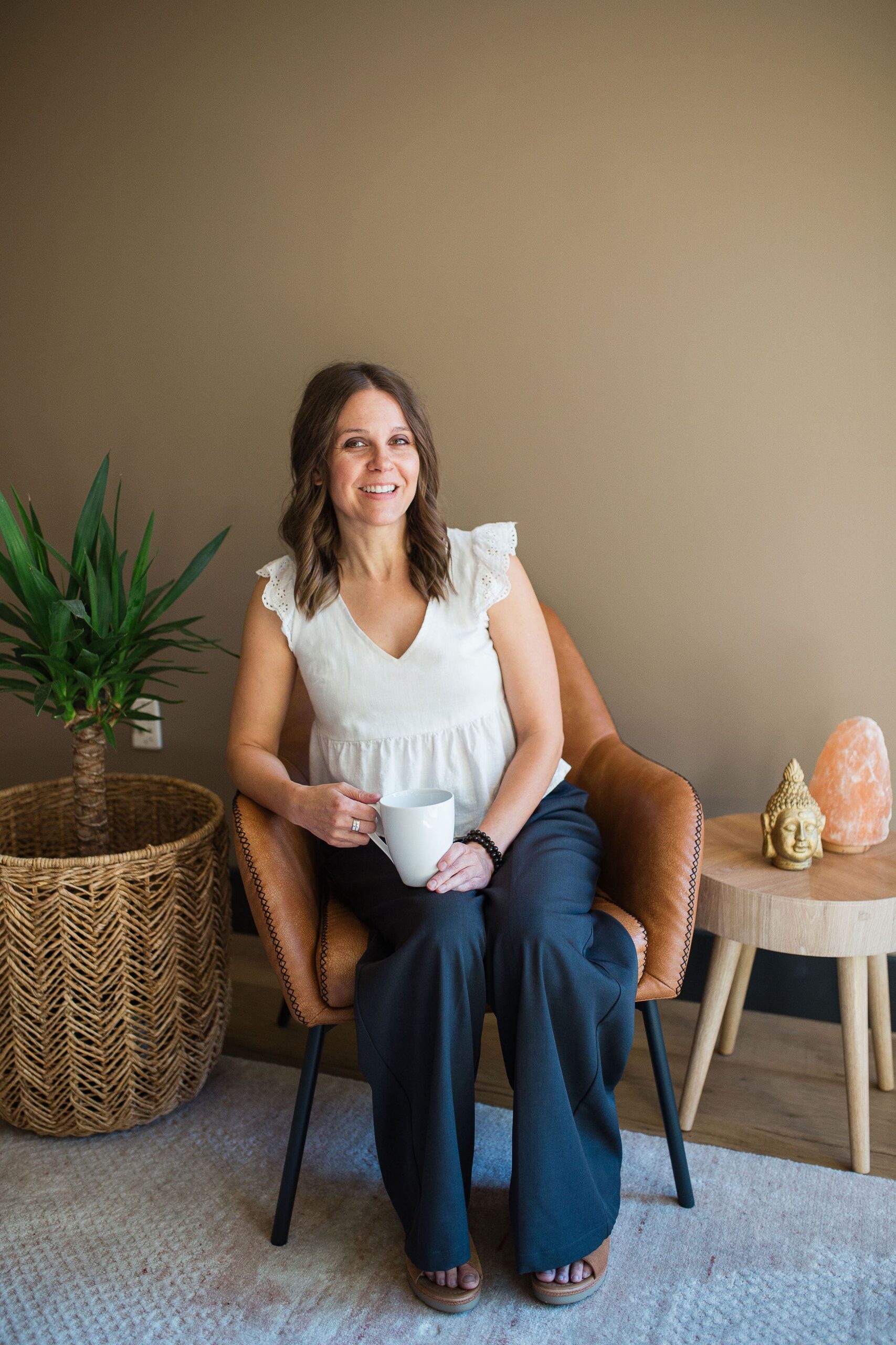 Ashley Kirkpatrick, therapist in Gilbert, Arizona specializing in breaking gender roles and helping men explore healthy masculinity, sitting in a chair holding coffee mug